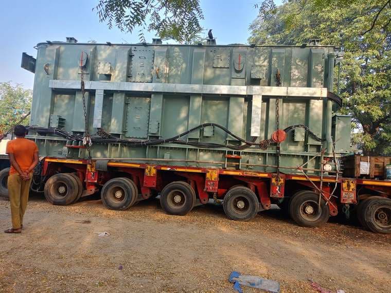 Power transformer strapped down on a multi-axle hydraulic trailer, ready to move.