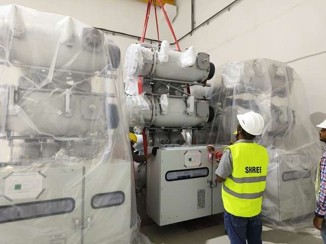 Gas-insulated switchgear module slung on webbing and positioned inside a substation hall.